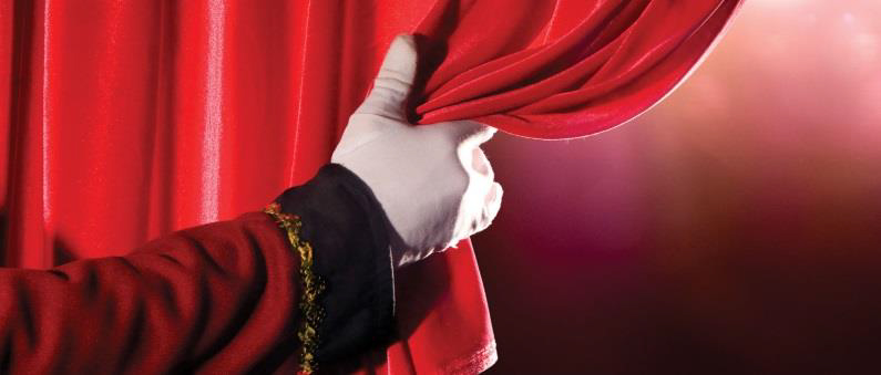 Photo of hand pulling back theatre curtain